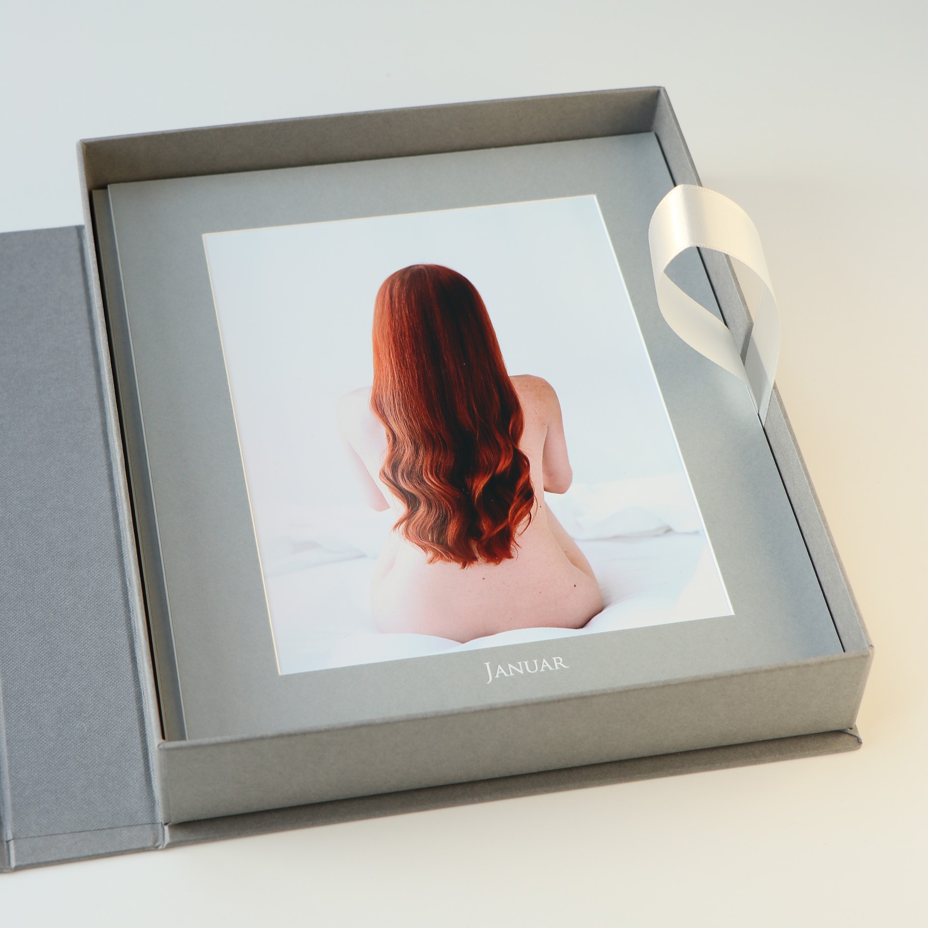 Kalenderbox 20x25cn, für 12 Kalenderpassepartouts mit Prägung der Monatsnamen. Hier Passepartout in Grau, Prägung in Weiß