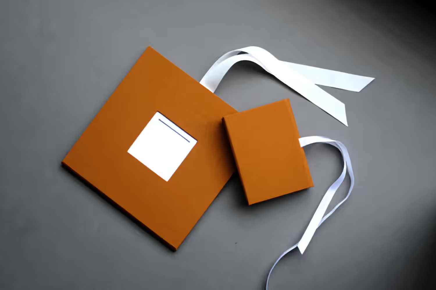 Braunes Folio mit Fensterausschnitt und weißem Satinband